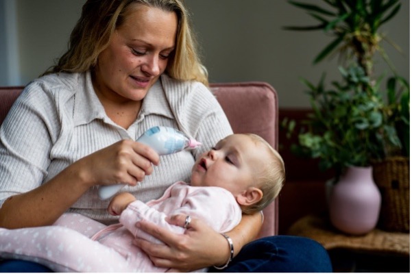 Women using nasal aspirator on baby